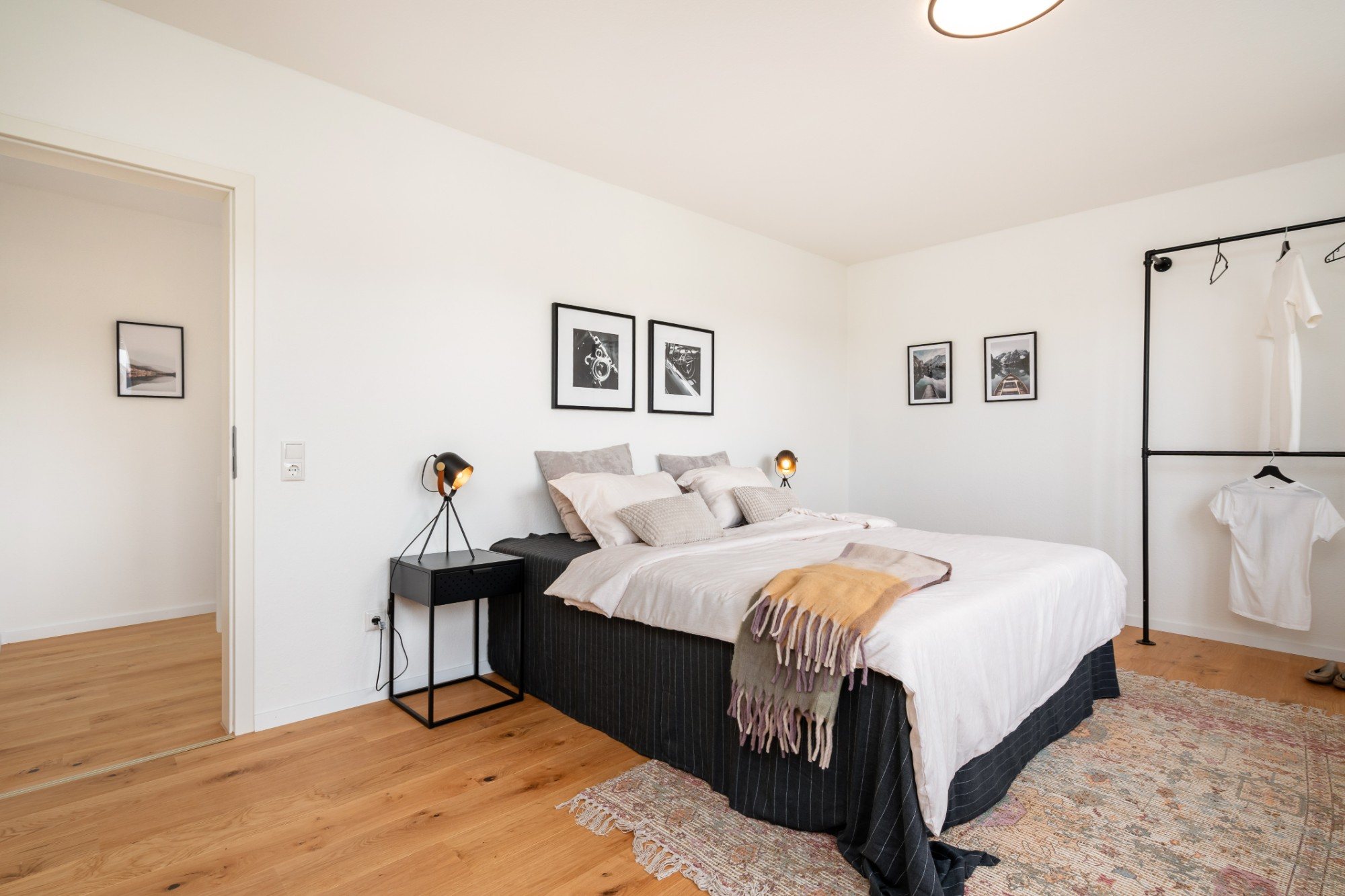 Schlafzimmer mit Doppelbett, Nachttischleuchten und offener Kleiderstange