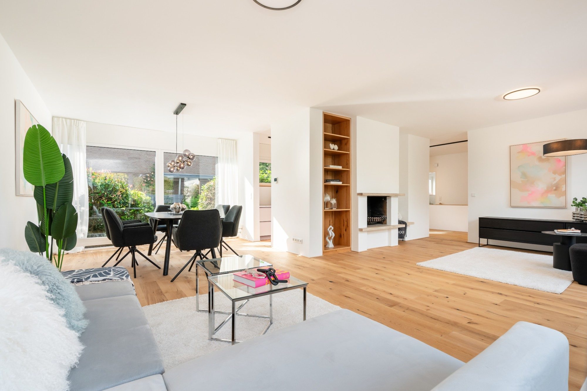 Offener Wohnbereich mit Kamin, Essplatz und bodentiefen Fenstern zum Garten