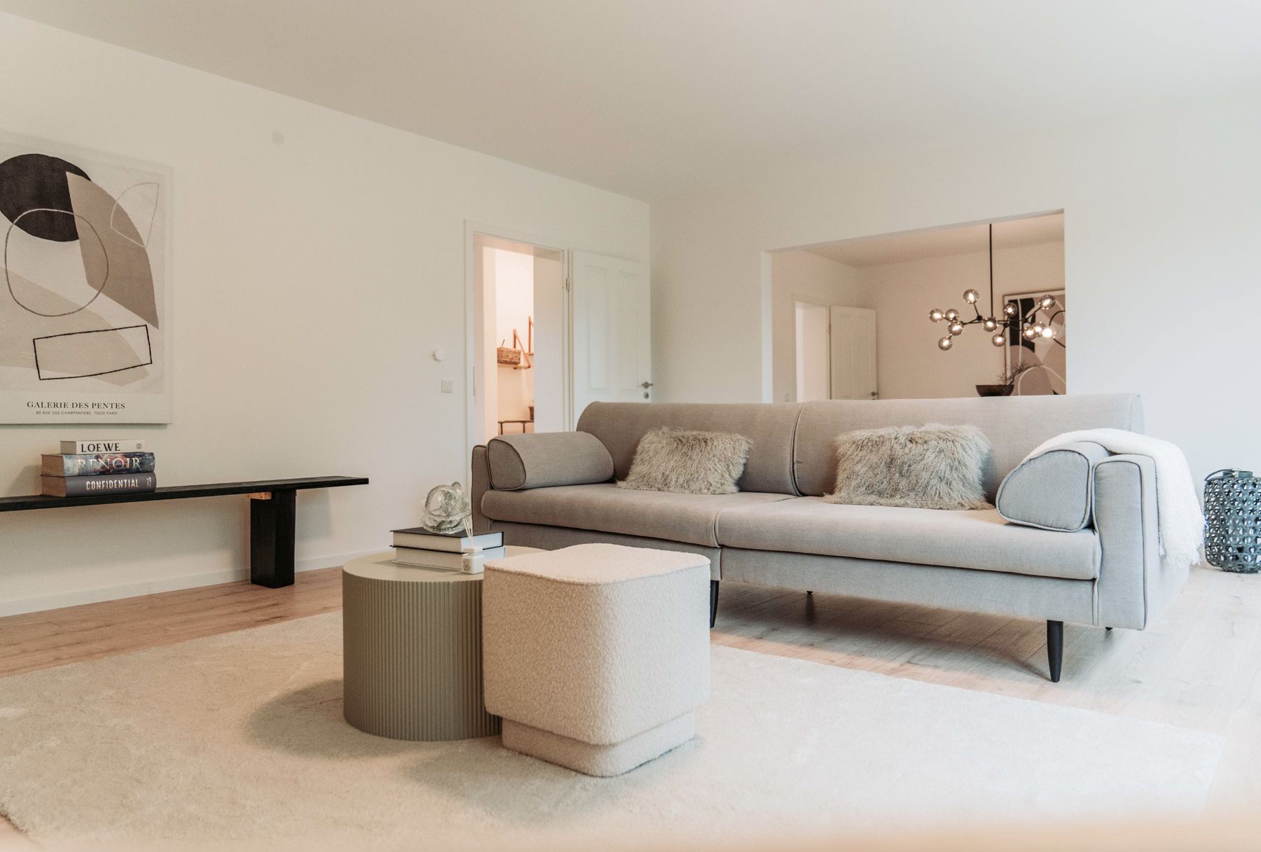 Wohnbereich mit Sofa, Sitzhockern und Durchblick ins Esszimmer